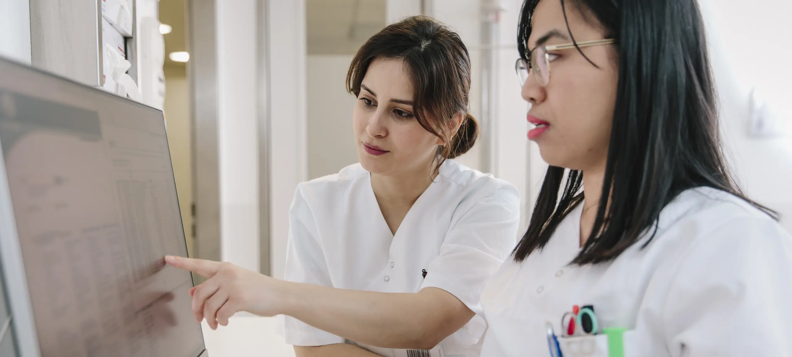 Zwei Gesundheitsfachkräfte betrachten gemeinsam einen Computerbildschirm und diskutieren Daten.