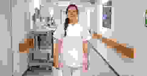 Eine Person in weißer Berufskleidung geht durch einen Krankenhausflur.