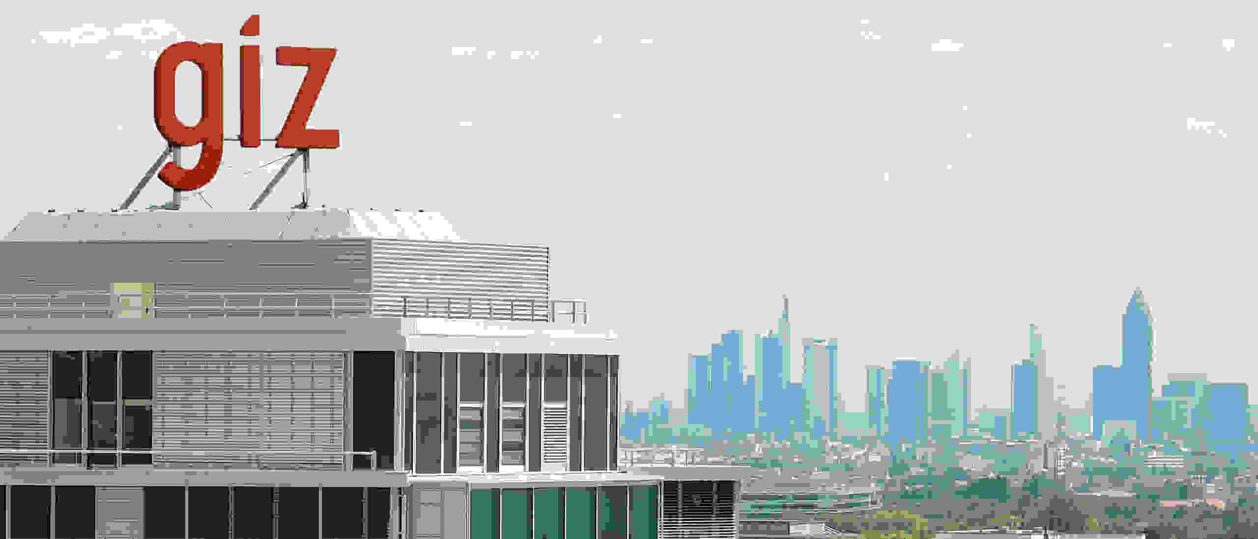 A modern office building with the red lettering “giz” on the roof and the skyline of a city in the background.
