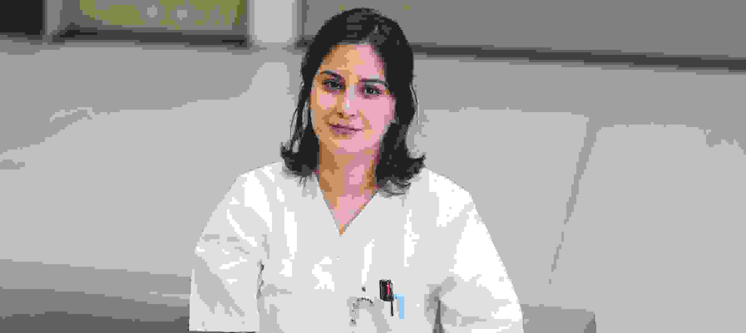 Une personne portant une blouse blanche de médecin est assise sur un canapé dans un intérieur moderne.