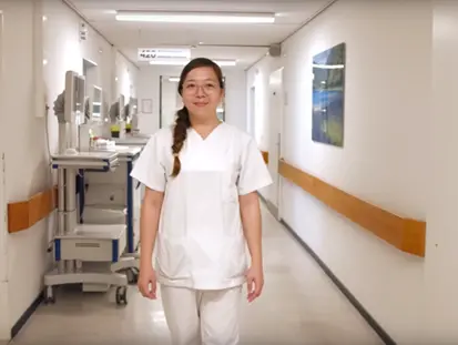 Une personne en tenue professionnelle blanche marche dans un couloir d'hôpital.