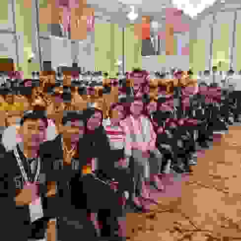 Photo de groupe de participants à une manifestation dans une salle où sont assises de nombreuses personnes portant des gilets orange. Des affiches avec des photos de dirigeants sont visibles à l'arrière-plan.