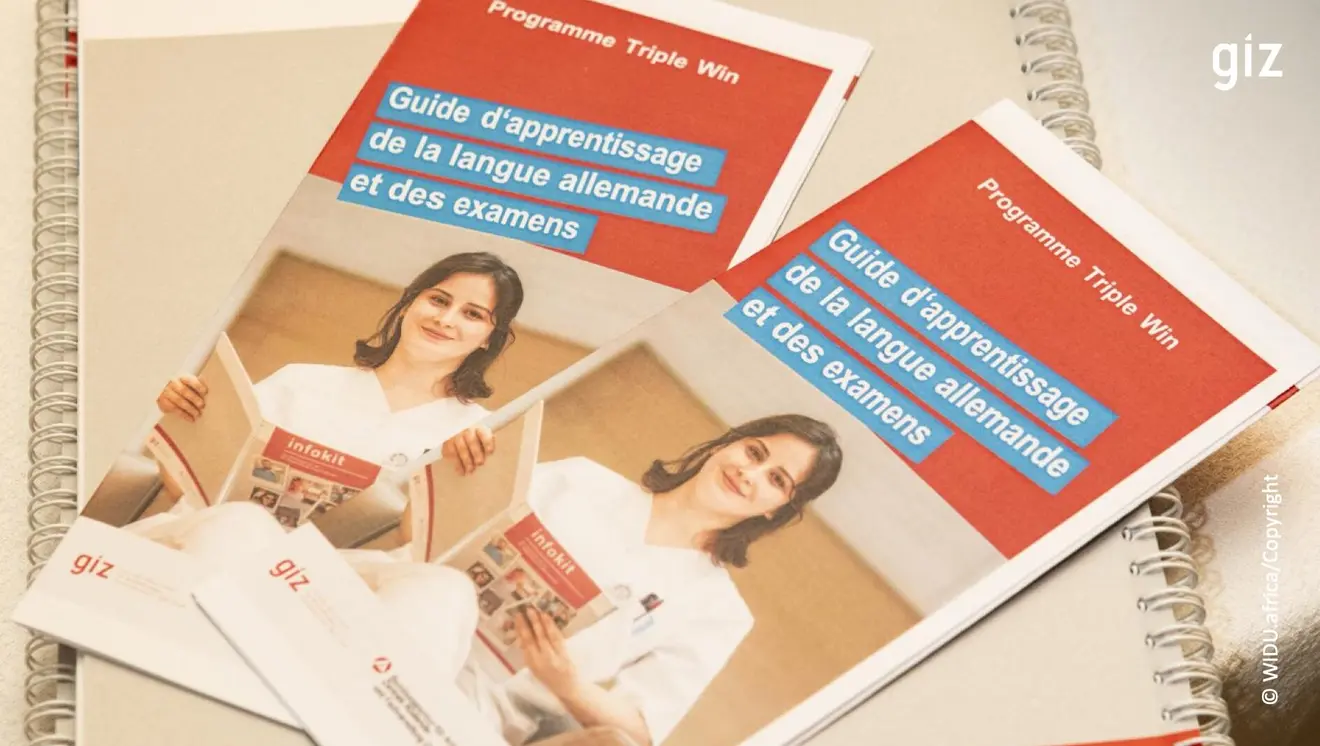Two brochures entitled “Guide to learning German and taking exams” written in French lie on a table, surrounded by a notebook.