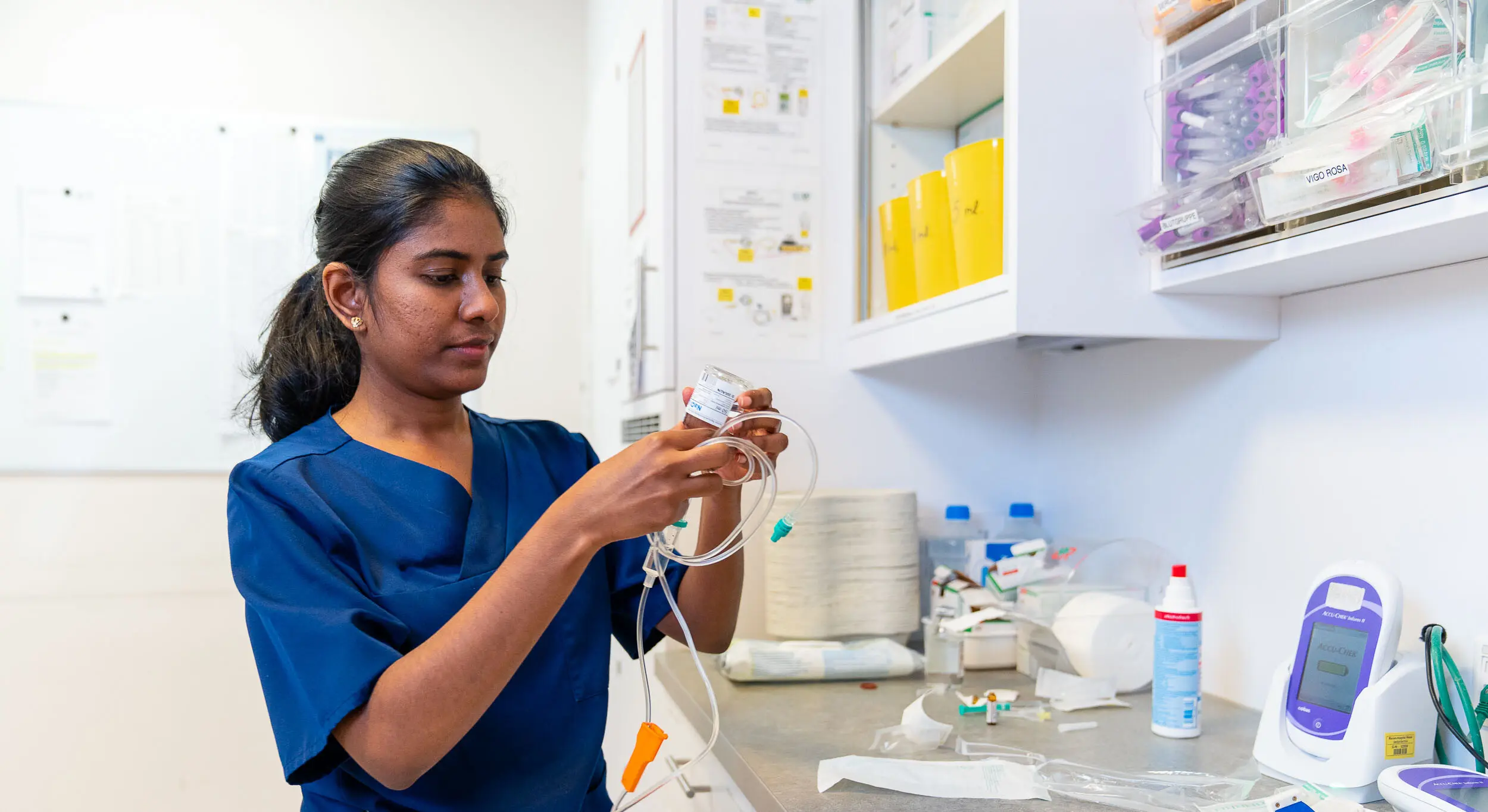 A specialist in blue uniforms works on medical equipment and accessories in a clinical environment.
