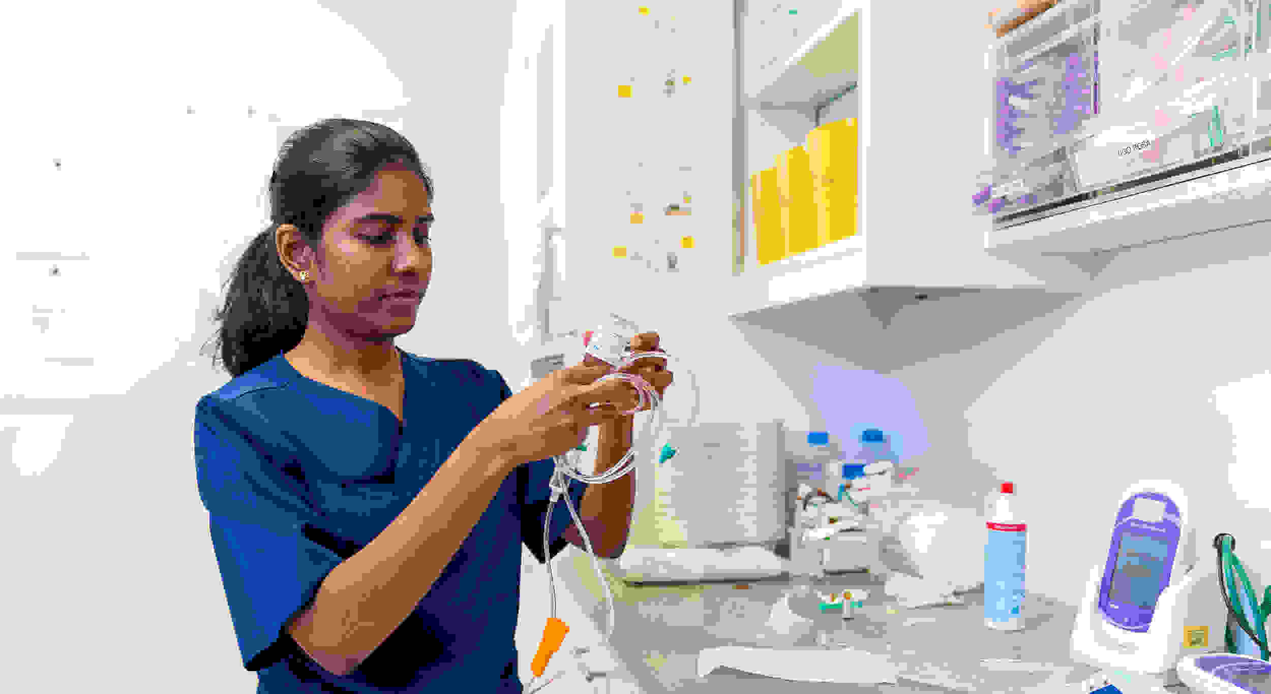 A specialist in blue uniforms works on medical equipment and accessories in a clinical environment.